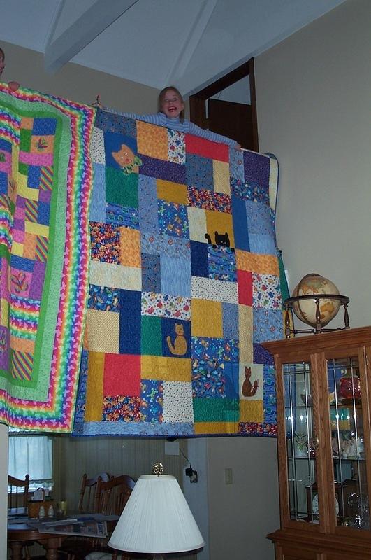 Elizabeth holds her quilt over the landing.